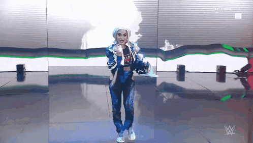 a woman in a blue jacket and pants is standing in front of a wall with a w logo on it