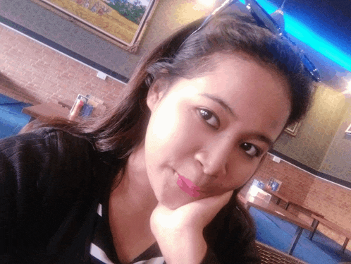 a woman taking a selfie with her hand on her chin in a restaurant
