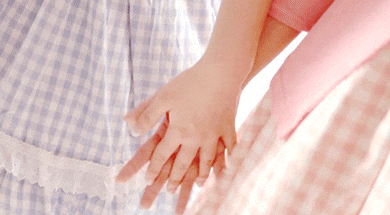 a woman in a blue and white checkered dress holds the hand of another woman in a pink dress .