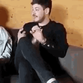a man is sitting on a couch with his legs crossed and holding his foot .
