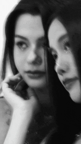 a black and white photo of a woman looking at herself in the mirror