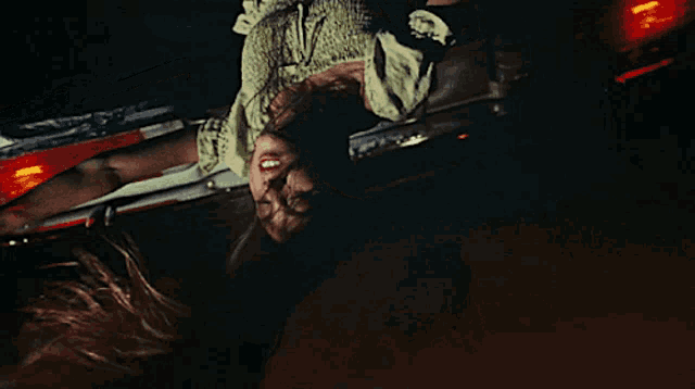 a woman in a green dress is upside down in a dark room