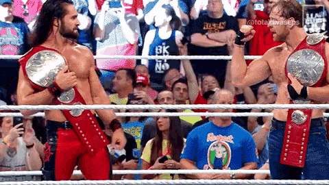 two wrestlers standing in a ring with their championship belts