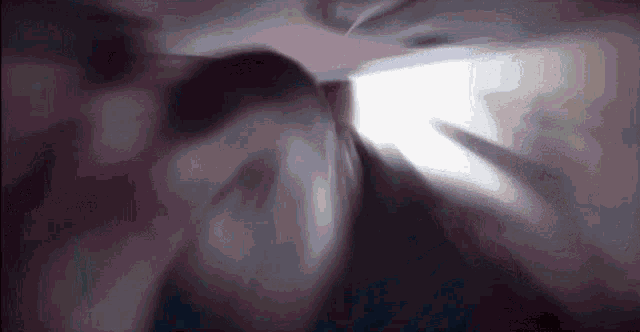 a blurry picture of a person in a dark room with a light coming through the window