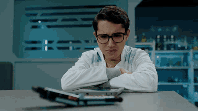 a young man wearing glasses sits at a table