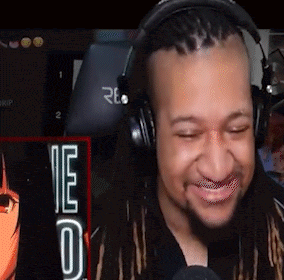 a man with dreadlocks is wearing headphones and smiling while playing a video game .