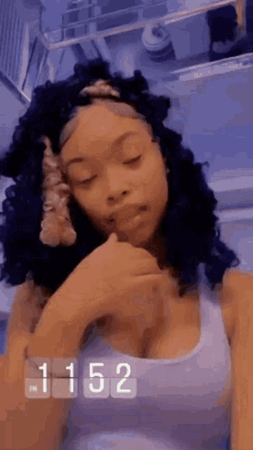 a woman with curly hair is taking a selfie with her eyes closed and her hand on her face .