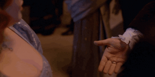 a woman wearing gloves is holding a man 's hand with a ring on it