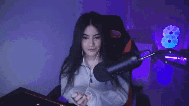 a woman is sitting in front of a microphone with a purple background