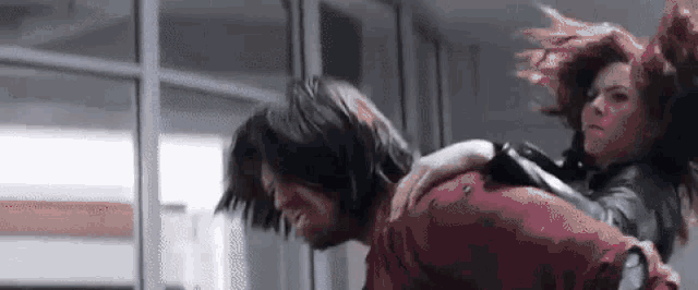 a woman is riding on the back of a man in a hallway .