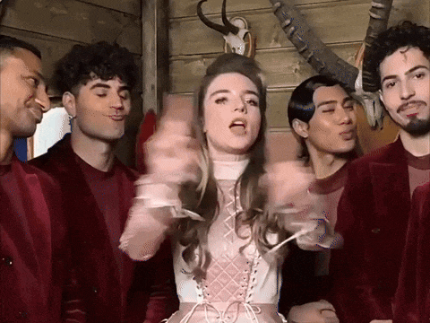 a woman in a pink dress is surrounded by a group of men in red jackets