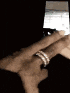 a person is wearing a ring on their finger and using a cell phone .