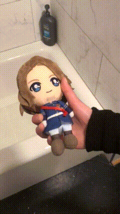 a person is holding a stuffed toy in their hand in front of a bathtub .