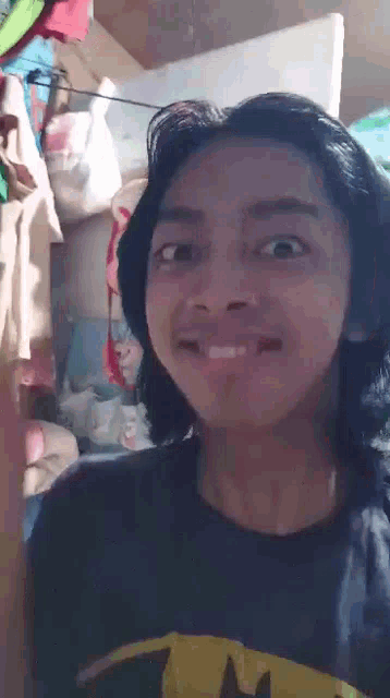 a young man with long hair is wearing a batman shirt