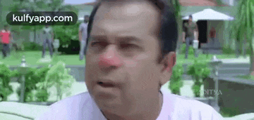 a man with a red nose is making a funny face while sitting on a couch .