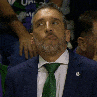 a man with a beard wearing a suit and tie with a pin that says ' ucsd '