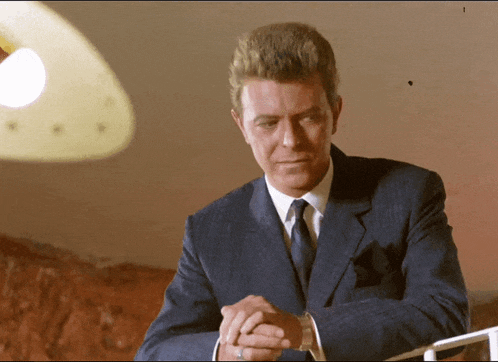 a man in a suit and tie has his hands folded in front of him