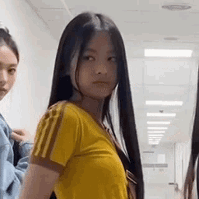 a woman with long black hair is standing in a hallway with another woman .