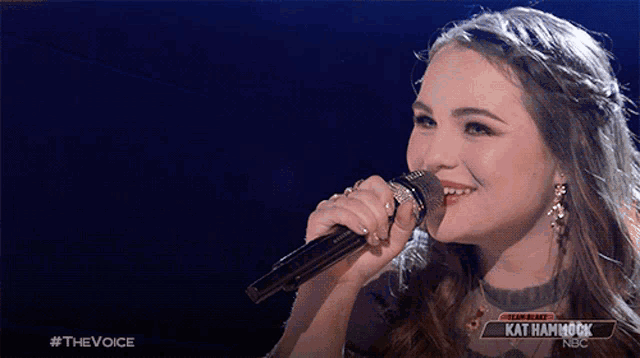 a woman singing into a microphone with kat hammock nbc in the corner