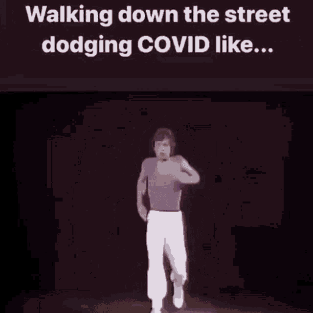 a man in a purple shirt is walking down the street and dodging covid like .