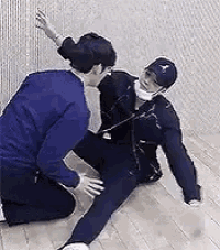 two men are kneeling on the floor and one of them is holding the other 's arm .