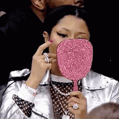 a woman is looking at herself in a pink mirror