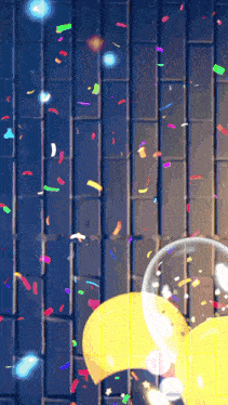 a brick wall with balloons and confetti coming out of it