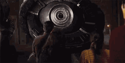 a man and a woman are looking at a large machine in a dark room .