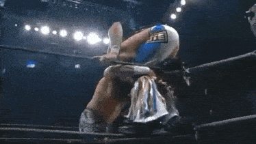 two men are wrestling in a wrestling ring with a crowd watching .