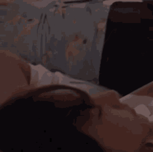 a person is laying on a bed with their head on a pillow .