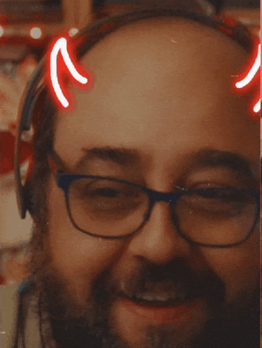 a man wearing glasses and headphones has devil horns on his forehead