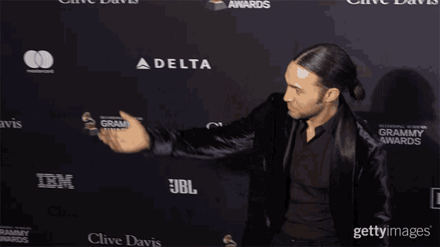 a man dancing on a red carpet in front of a delta jbl and clive davis logo