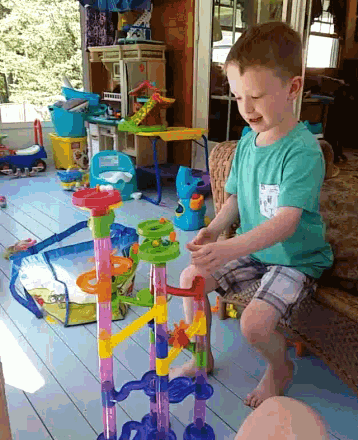 a young boy in a green shirt with a pocket that says ' i love you ' on it is playing with a toy