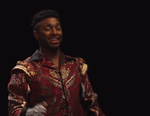 a man in a red and gold jacket holds his hands up