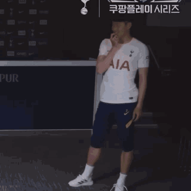 a man wearing a white aia shirt is standing in front of a sign that says pur