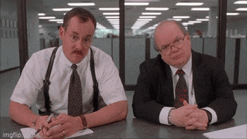 two men are sitting at a table with their hands folded in front of them .