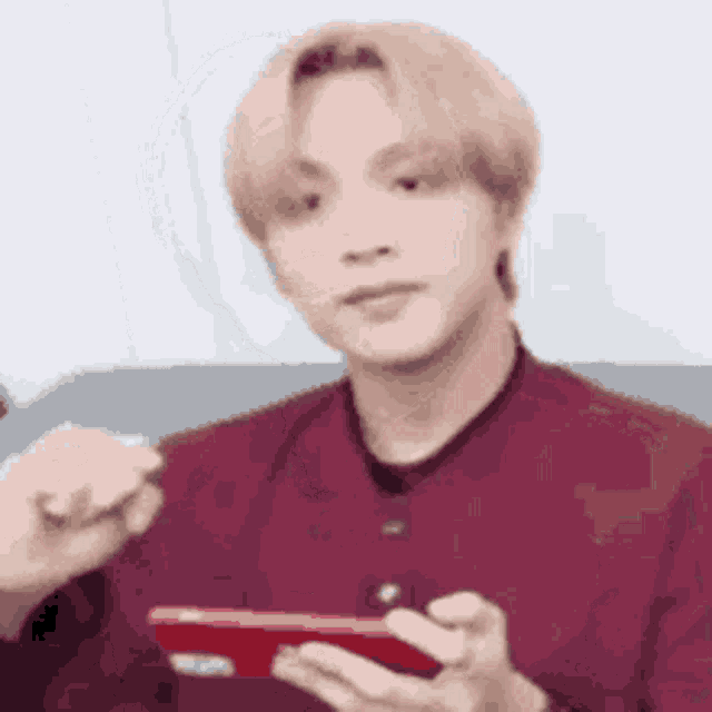 a man in a red shirt is holding a red phone in his hand .