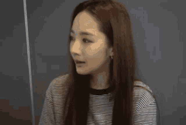 a woman with long hair is wearing a striped shirt .