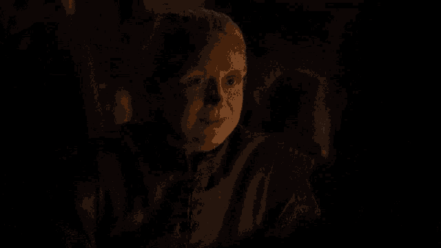 a baby yoda looking at a cell phone in a dark room with lit candles