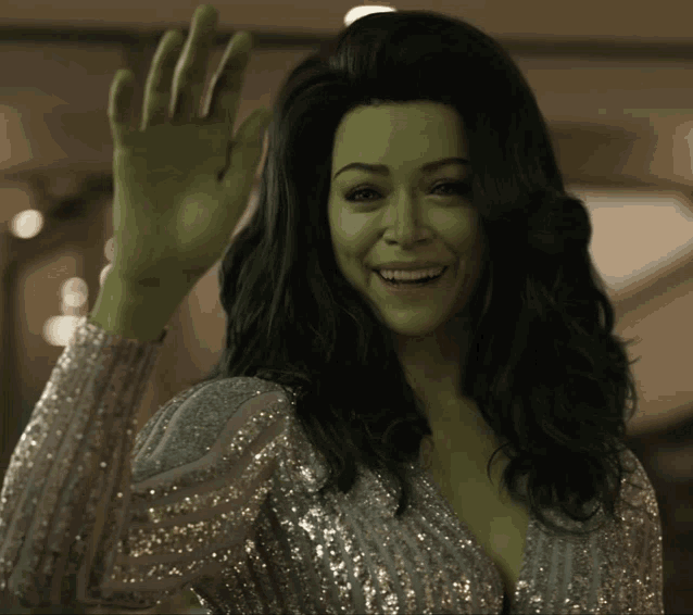 a woman with green hair is waving her hand and smiling