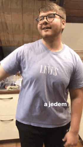 a man wearing a levi 's t-shirt stands in a kitchen