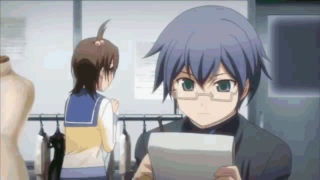 a boy with glasses is holding a piece of paper while a girl stands behind him