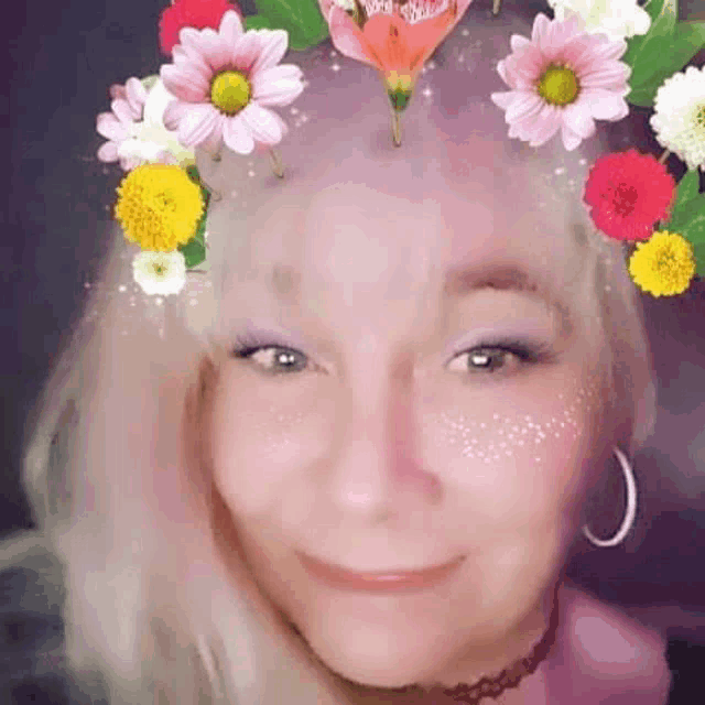 the woman is wearing a flower crown on her head and smiling .