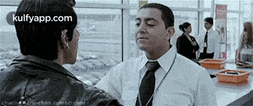 a man in a white shirt and tie is talking to another man in a black jacket .