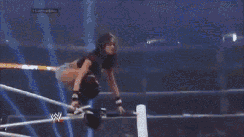 a referee is standing in a wrestling ring with a crowd watching a match .