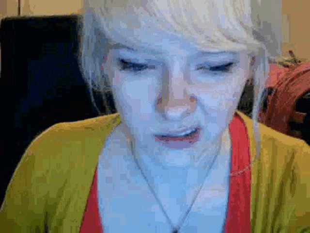 a woman with blonde hair is wearing a yellow cardigan