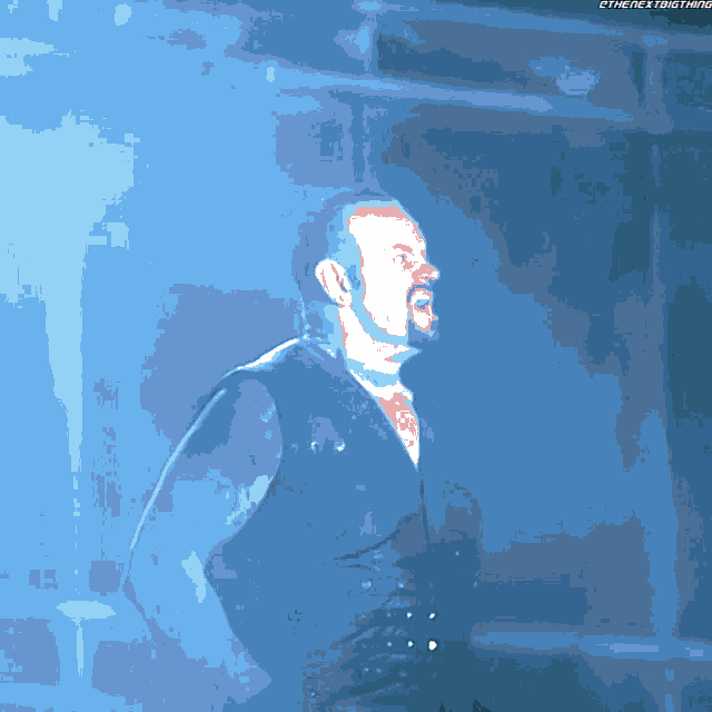 a man in a leather vest stands in a dark room with a blue background