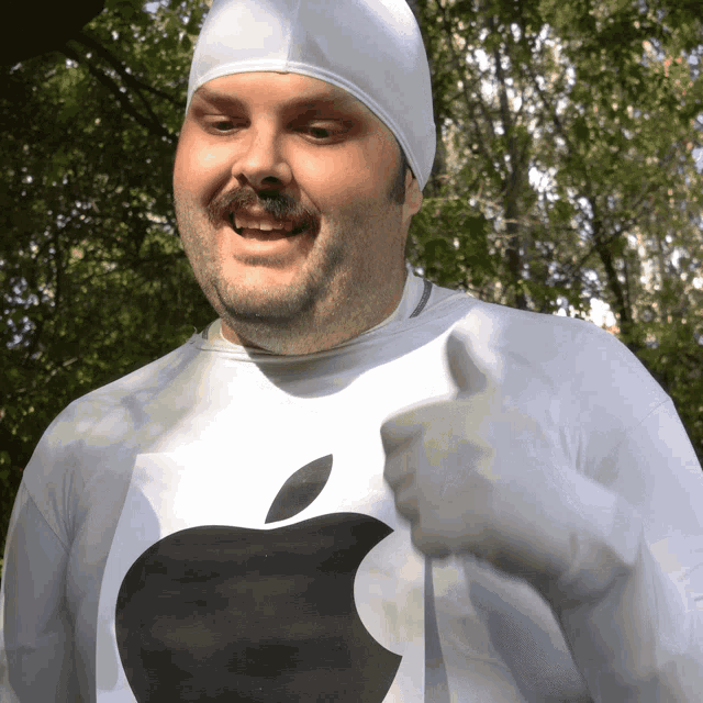 a man wearing a white shirt with an apple on it gives a thumbs up