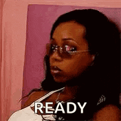a woman wearing sunglasses and a white tank top is sitting on a bed and says `` ready '' .