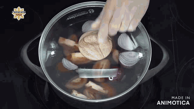 a pot of mushrooms and onions is being stirred with a wooden spoon and the words made in animotica visible